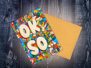 Colorful greeting card with 'OK SO' text on a wooden surface