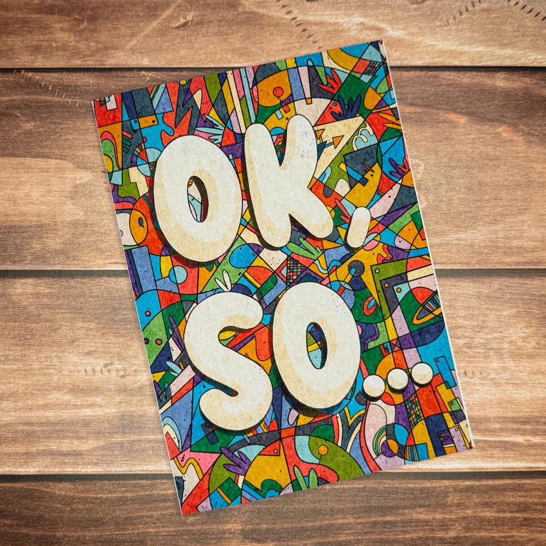 Colorful notebook with 'OK, SO.' text on a wooden surface