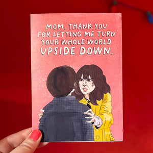 Card with illustration of a woman and child, text 'Mom, thank you for letting me turn your whole world upside down' on a red background.